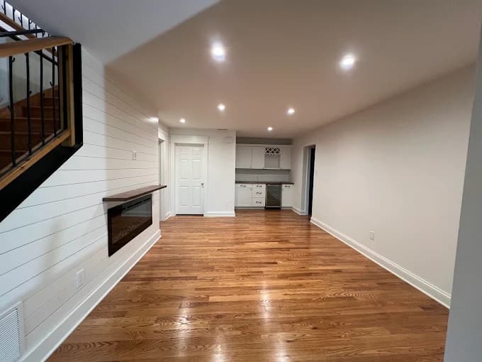 Interior painting project by JV Painting Services in Hendersonville, NC. The image shows a room with beige walls, white trim, wood floors, and recessed lights.