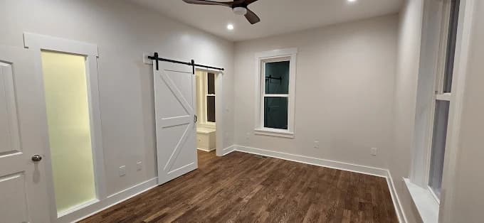 Interior painting project by New Life Painting LLC in Clayton, North Carolina. The image shows gray walls, white trim, wood floors, and a white barn door.