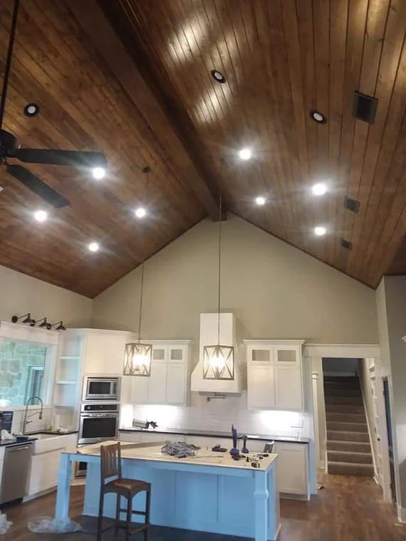 "This is an image from Reeves Painting, located in Texas. The interior photo shows a kitchen with a vaulted wood ceiling, pendant lights, white cabinetry, and a center island."