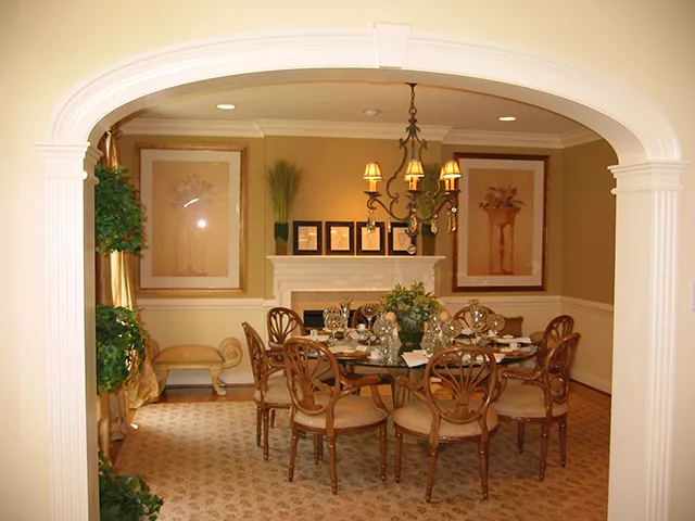 This is an image from Donovan’s Painting, located in Maryland. The photo shows a warmly lit dining room with soft beige walls, framed artwork, and a decorative chandelier over a formal dining table.