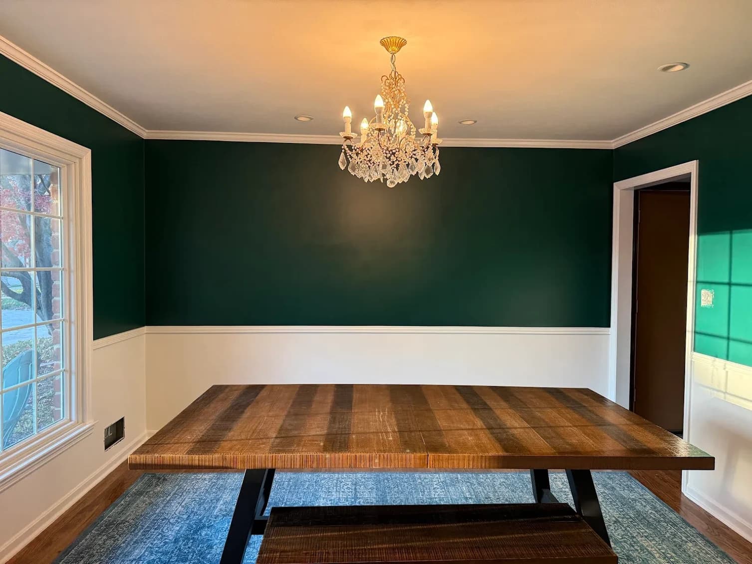 This is an image from Mission Painting and Home Improvements. The image shows a dining room interior with dark green upper walls, white wainscoting, and detailed trim.