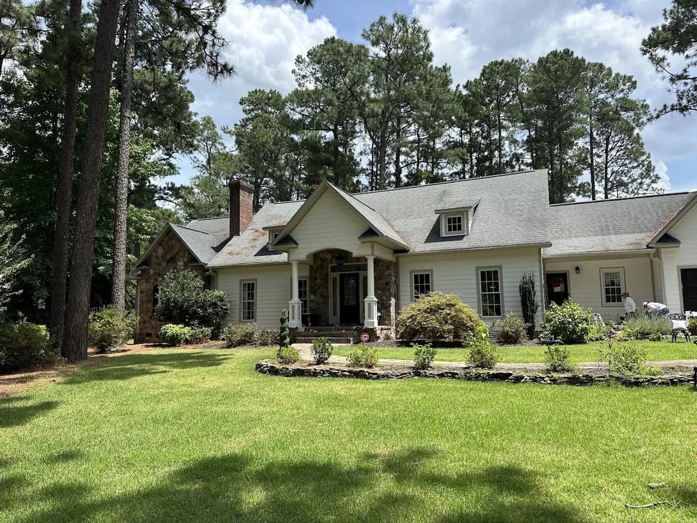 Exterior painting project by 360° Painting of Pinehurst in Southern Pines, NC. The image shows a cream home, green lawn, trees, and front landscaping.