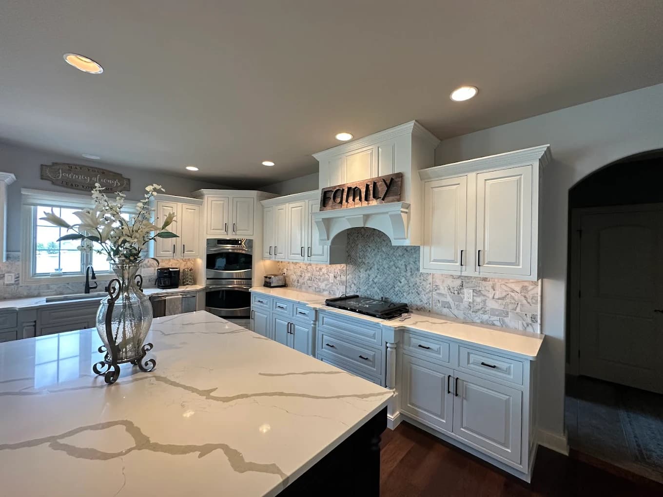 Cabinet painting by D J's Painting and Remodeling Inc in Bloomington, Illinois. The image shows white and gray cabinets, stone counters, and tile backsplash.