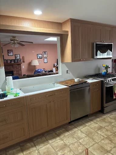 This is an image from BEE Pro Painting, located in New Jersey. The image shows a refreshed kitchen with newly painted wood cabinets, clean wall finishes, stainless steel appliances, and updated trim details.