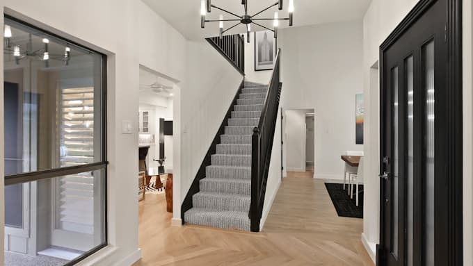 This is an image from Big Al's Painting, located in Texas. The photo shows a modern interior entryway with a central staircase, black accents, light wood flooring, and bright white walls.