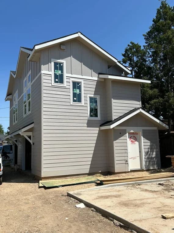 This is an image from Montenegro's Painting & Construction LLC company, located in Meridian, ID The image is a two-story home exterior freshly painted in light beige with white trim during new construction phase by Montenegro's Painting & Construction, LLC