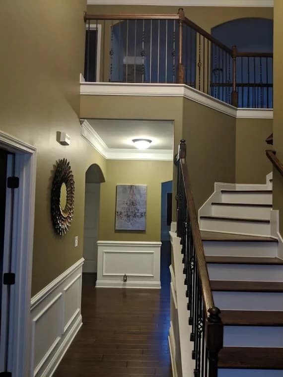 Interior painting project by 360° Painting of Lake Norman in Charlotte, NC. The image shows olive walls, white wainscoting, stairs, and wood floors.