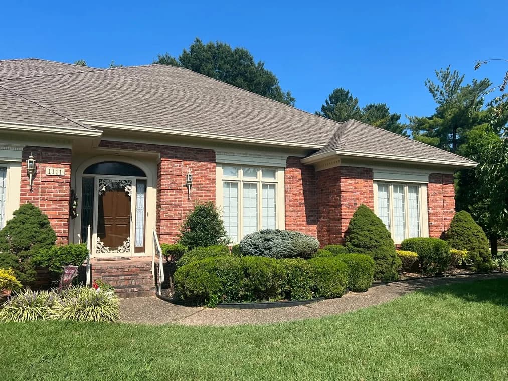 This is an image from Snap Painting Plus, located in Kentucky. The image shows a brick home exterior with freshly painted trim, a clean front entryway, and neatly maintained landscaping.