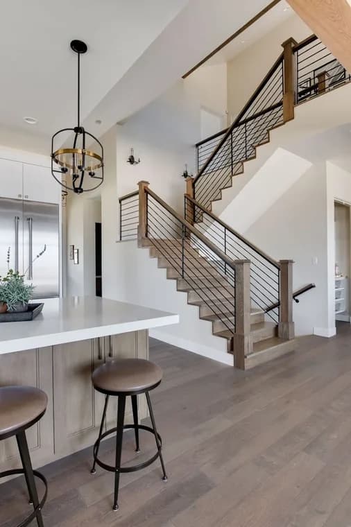 This is an image from J & S Painting Plus, located in New York. The interior image shows a modern kitchen and staircase area with wood accents, metal railing, bar stools, and neutral wall colors.