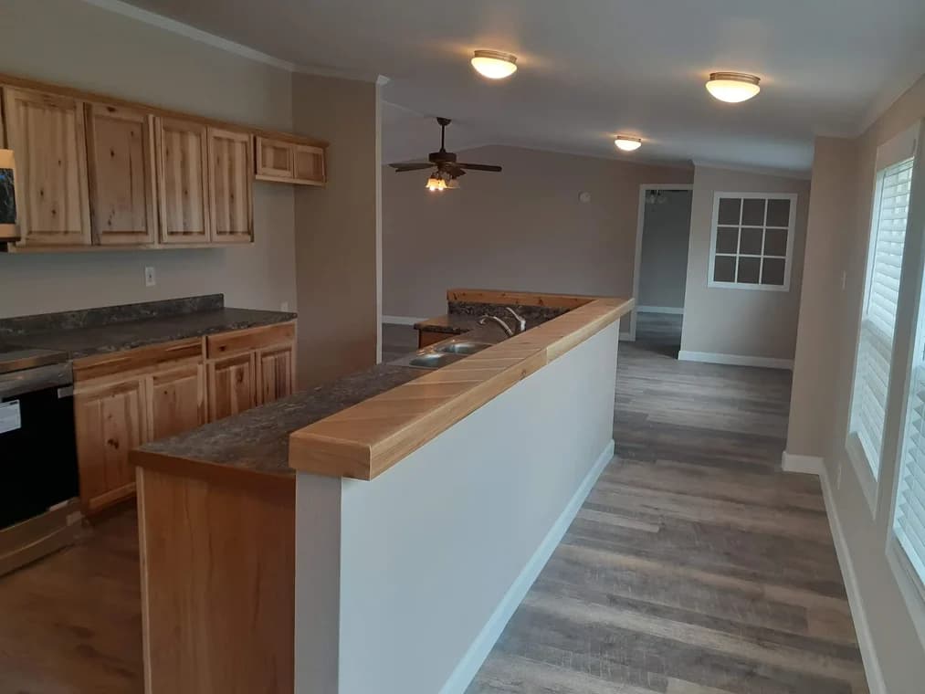 "This is an image from James Painting & Remodeling, located in Texas. The image shows an updated interior space with wood cabinets, new countertops, neutral painted walls, and wood-look flooring."
