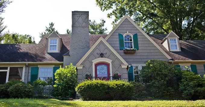 This is an image from Whitehouse Residential & Commercial Painting, located in Kentucky. The image shows a freshly painted traditional home exterior with light siding, contrasting shutters, detailed trim work, and mature landscaping.