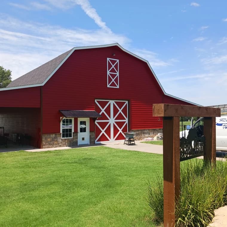 Exterior of a large red barn painted by Remarkable Painting, with white trim and a stone foundation, showcasing the company’s expertise in exterior painting for rural and agricultural properties.