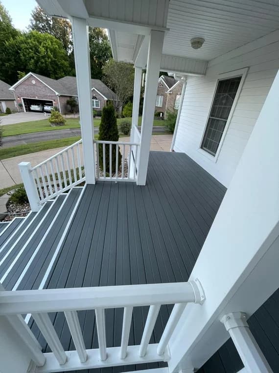 This is an image from Rodgers Painting, located in Kentucky. The photo shows a freshly painted front porch with clean white railings and dark gray decking overlooking a quiet suburban neighborhood.