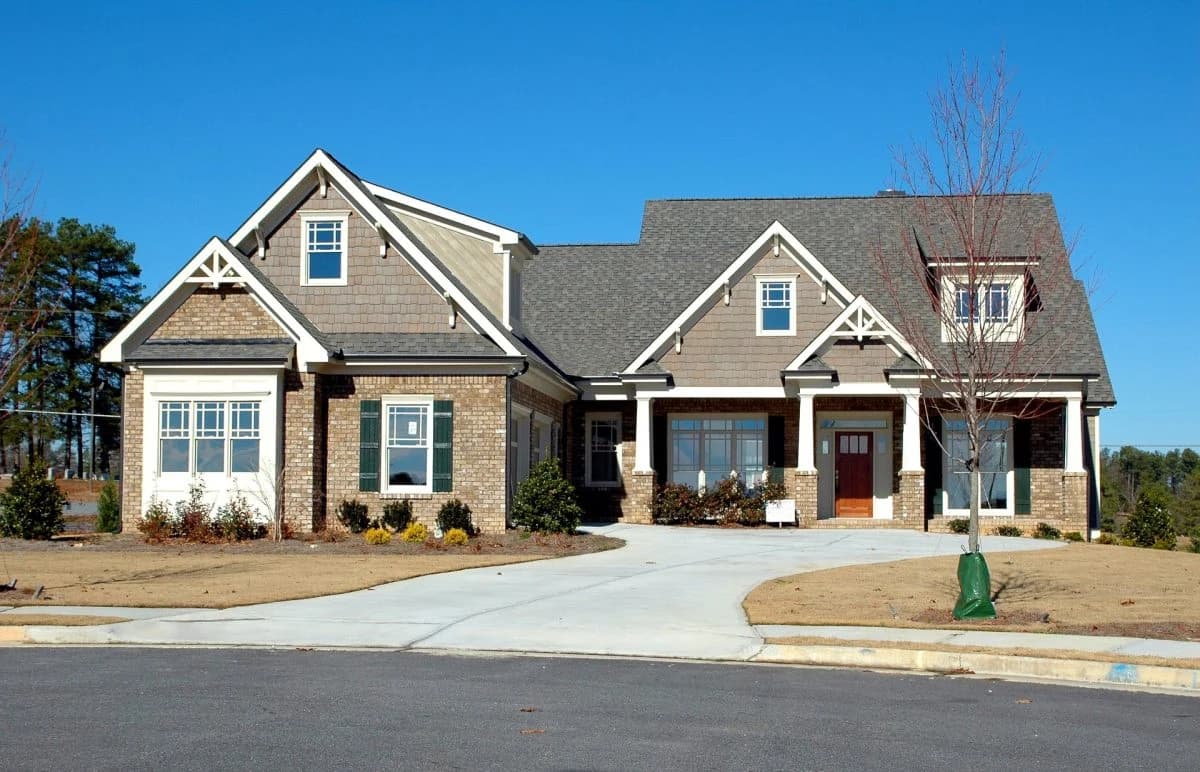 This is an image from River City Painting Inc. The image shows a large craftsman-style home with mixed brick and shingle siding and newly painted trim.