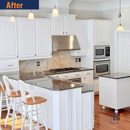 This is an image from 2 Cabinet Girls, located in North Carolina. The photo shows a modern kitchen with freshly refinished white cabinets, granite countertops, stainless steel appliances, and wooden barstools at the island.