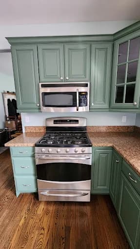 This is an image from Todd's Painting, located in New York. The image shows a kitchen with green painted cabinets, stainless steel appliances, and wood flooring.