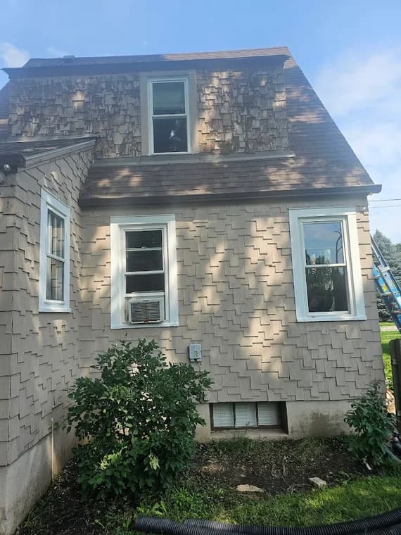 Exterior painting project by Marty Mar Construction, LLC in Chicago, IL. The image shows beige shingle siding, white trim, a steep roofline, and shrubs.