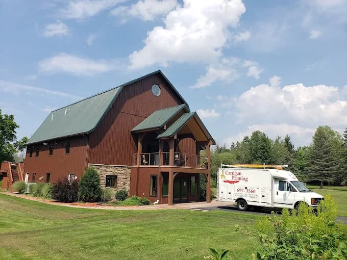 This is an image from Carrigan Painting, located in Wisconsin. The image shows an exterior commercial painting project featuring a large barn-style building with freshly painted siding and trim.