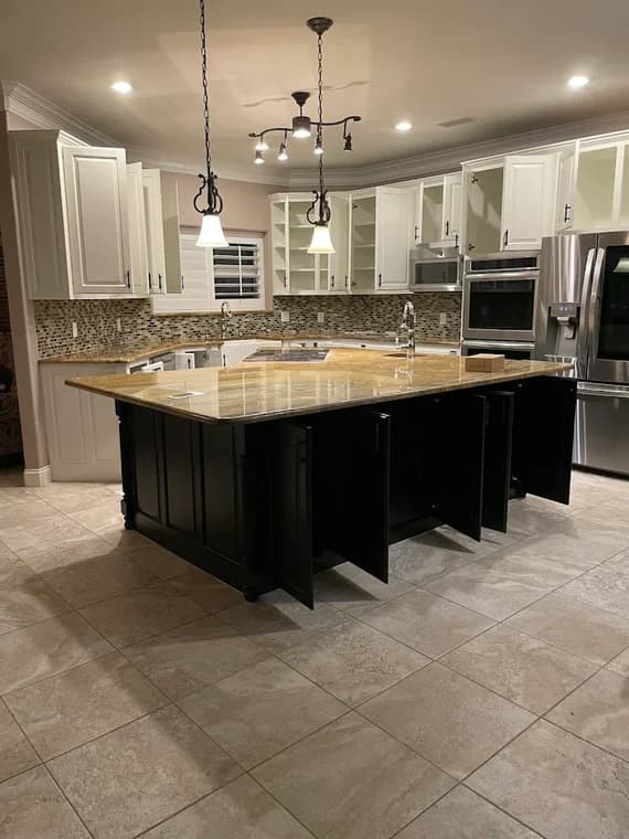 "This is an image from CertaPro Paintters of Lake Ray Hubbard, located in Texas. The photo shows a remodeled kitchen with white cabinetry, a large island with dark lower cabinets, stainless steel appliances, and tile flooring."