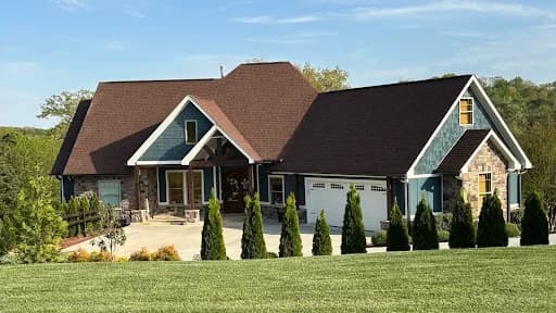 Painting project by Good Faith Painting Company in Knoxville, Tennessee. The image shows a dark green cottage with cream trim and a steep brown roof.