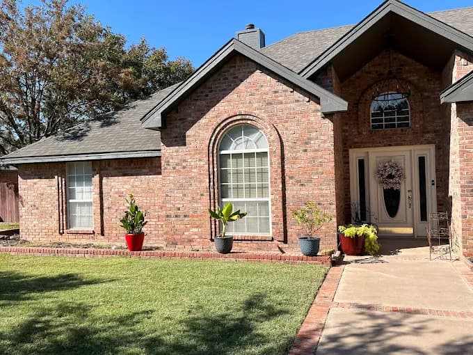 "This is an image from Alvarez Painting, located in Texas. The image shows a brick home exterior with neatly painted trim and a well-maintained lawn under clear skies."