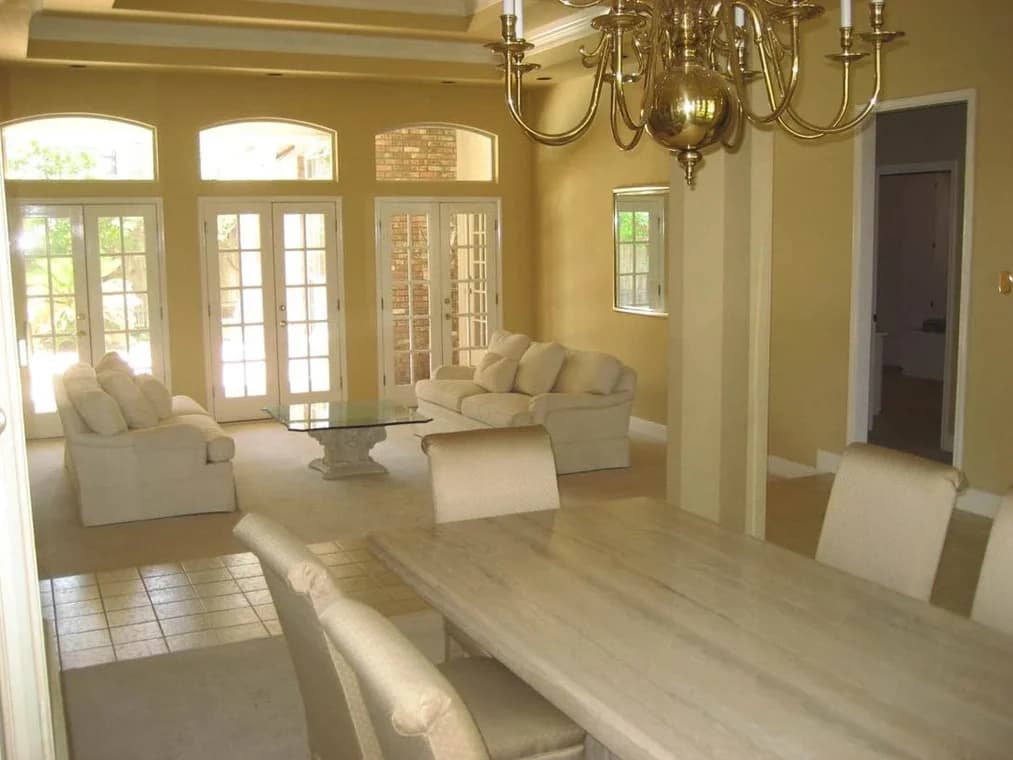 This is an image from CertaPro Painters of San Antonio, located in Texas. The interior image shows a dining and living room space with beige walls, cream-colored furniture, and multiple French doors providing natural light.