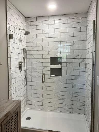 Painting work by Scott Brown Professional Painting & Remodeling in Chattanooga, Tennessee. The image shows a white tile shower with dark fixtures.