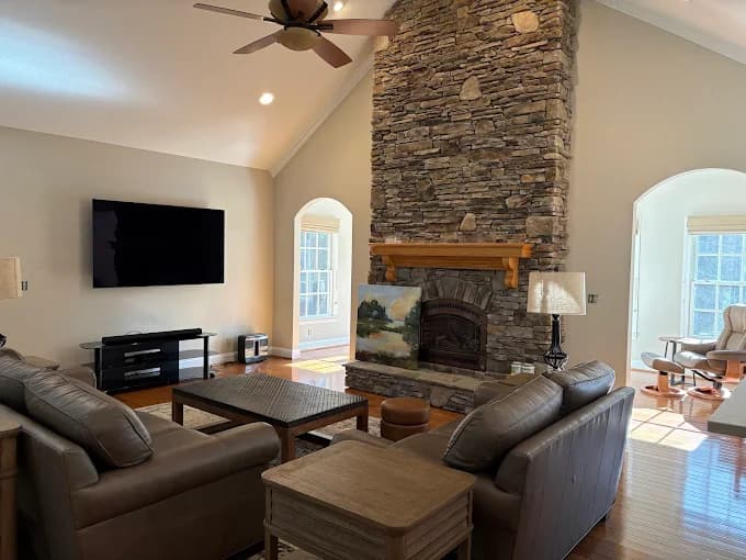 Interior painting project by Burlett Painting, LLC in Hendersonville, North Carolina. The image shows a stone fireplace, mounted TV, arched doors, and seating.