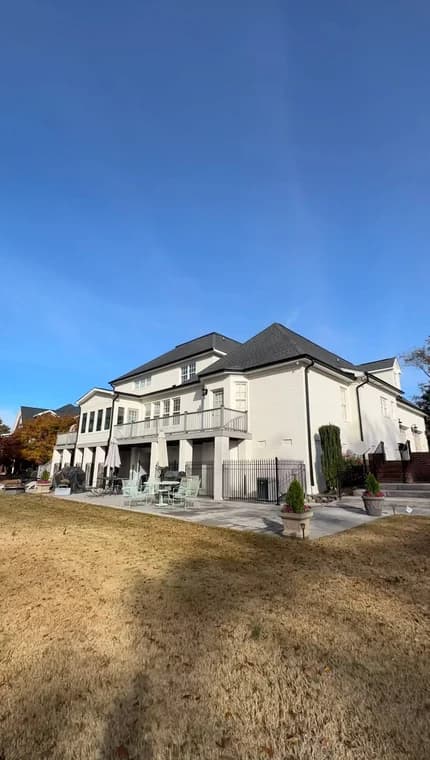 Exterior painting project by Mario's Painting NC in Clayton, NC. The image shows a large white two-story home with dark trim, balconies, and a broad lawn.