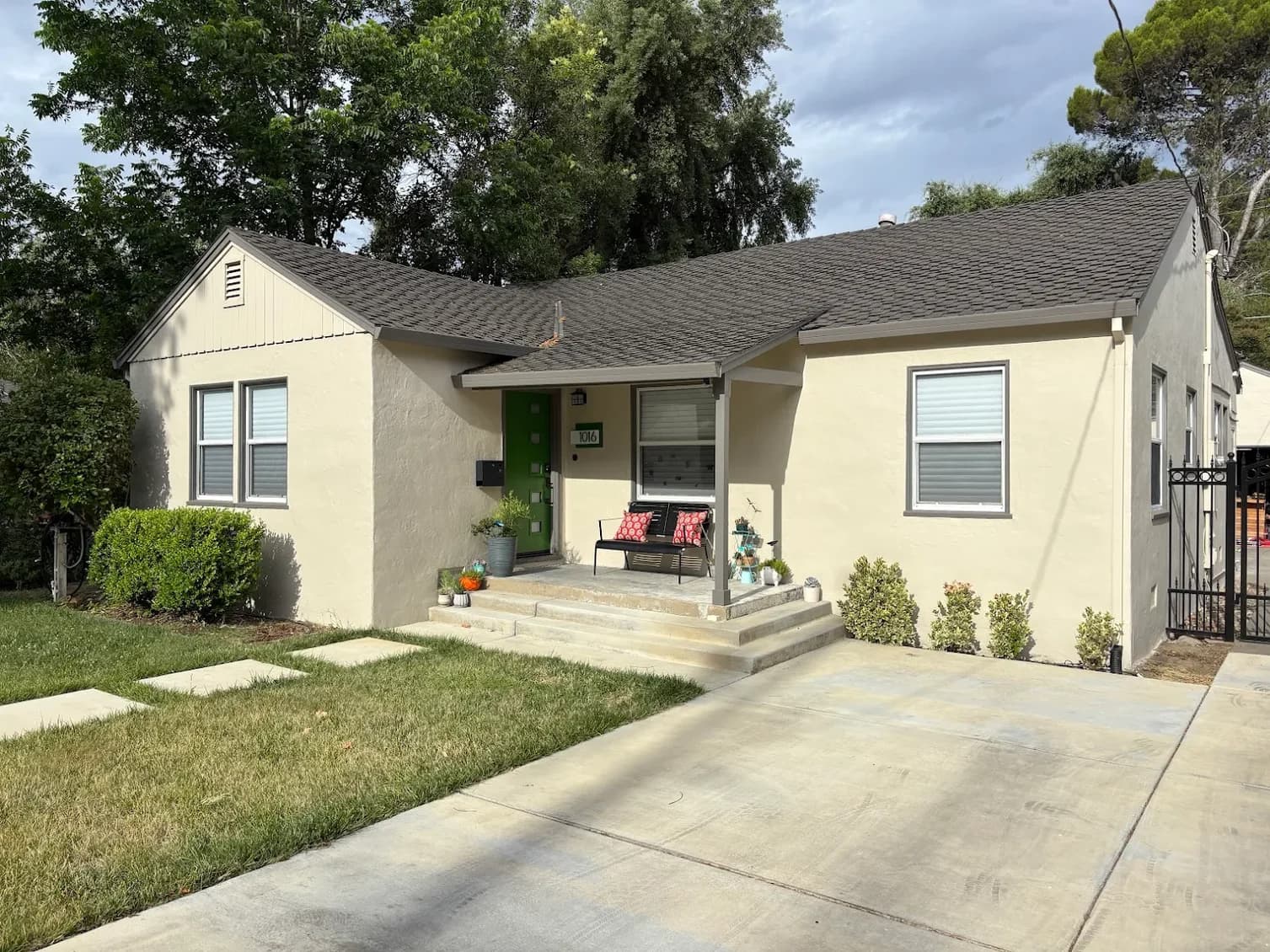 This is an image from Brooks Painting, located in California. The image is from Brooks Painting and shows exterior painting on a single-story beige home with a green front door, white trim, and a clean concrete driveway.