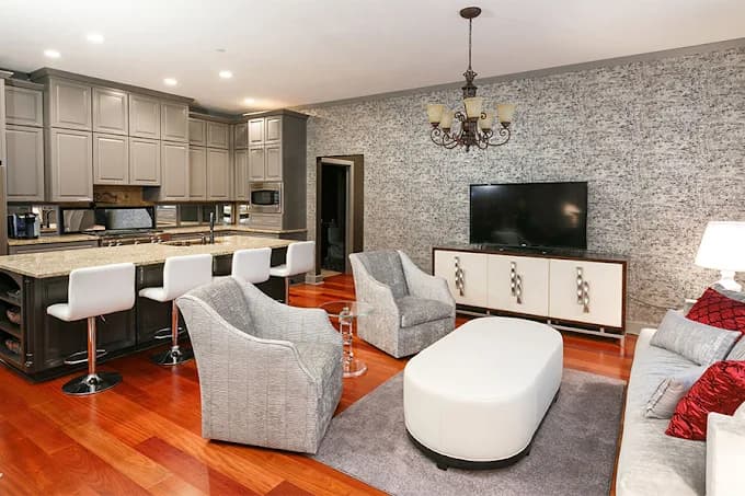 This is an image from Whitehouse Residential & Commercial Painting, located in Kentucky. The image shows a modern open-concept living space with freshly painted walls, updated cabinetry, accent wallpaper, and hardwood flooring.