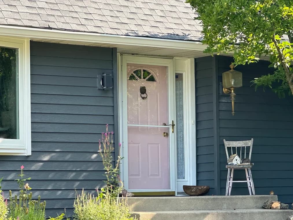 Exterior painting by D'franco Painting & Wallpaper in Huntley, Illinois. The image shows blue siding, white trim, a pink door, and a covered entry.