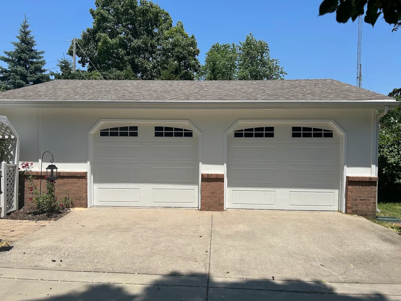 Exterior painting project by Total Coverage Painting in Bloomington, Illinois. The image shows a detached garage with light gray siding, white trim, and two white doors.