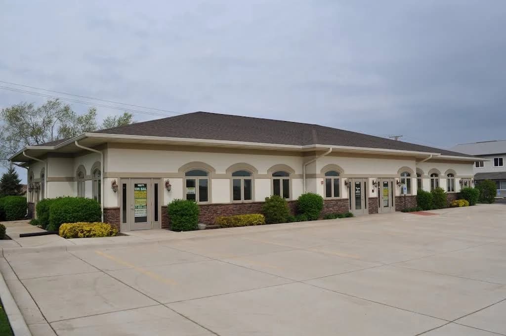 Commercial stucco project by JJ Stucco & Plastering System Inc. in Lake in the Hills, Illinois. The image shows a beige one-story building with arched windows.