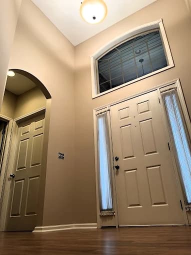 This is an image from Quick Painting LLC, located in Kentucky. The image shows a freshly painted interior entryway with neutral wall colors, white trim, an arched doorway, and a clean, modern residential finish.