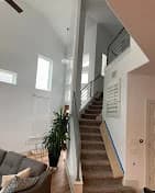 This is an image from VS Pro Painting, located in Texas. The staircase and interior walls are newly painted, highlighting tall ceilings, modern railing, and clean white finishes.