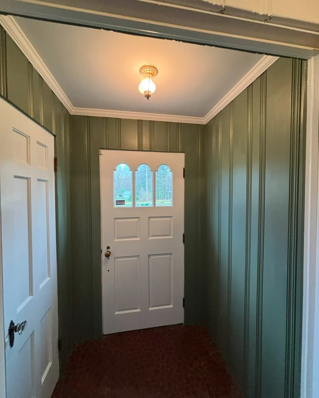 This is an image from 216 Painting, located in Ohio. The image shows a freshly painted entryway with green vertical panel walls, white trim, a light blue ceiling, and a white front door with decorative glass inserts.