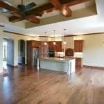 This is an image from West & Co Painting, LLC. The image shows a spacious open kitchen and living area with wood floors, exposed ceiling beams, and warm natural light.