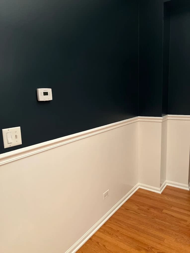 Interior painting project by Jung Family Painting in Naperville, IL. The image shows dark teal walls above white wainscoting, white trim, and hardwood flooring.