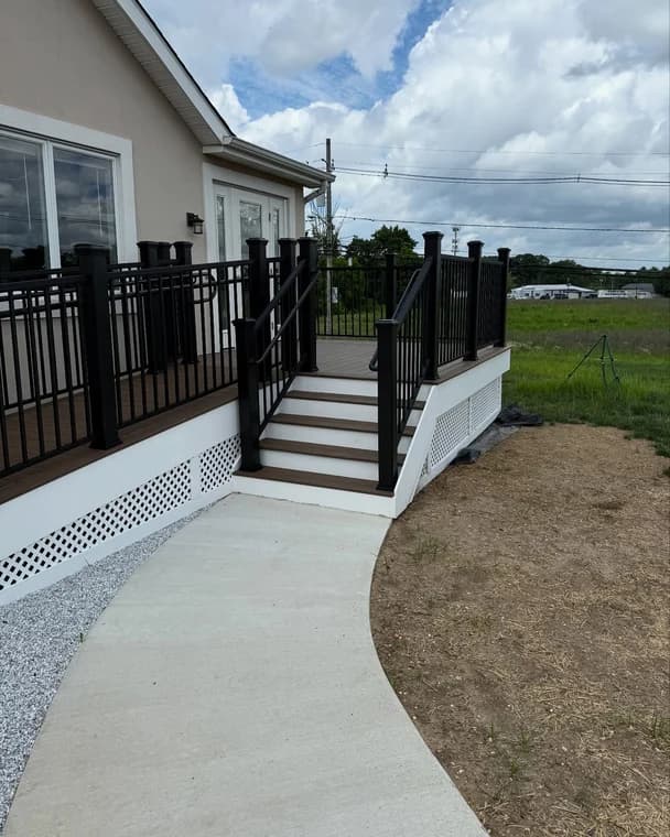 A modern home exterior painted in light gray siding with white trim, surrounded by a neat lawn and shrubs, completed by Bucci Paint.