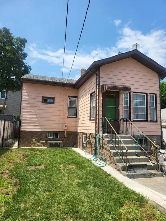 This is an image from CertaPro Painters of Staten Island, located in New York. The picture shows a peach-colored home exterior with brown trim, newly painted siding, and a small front entry staircase leading to a green front door.