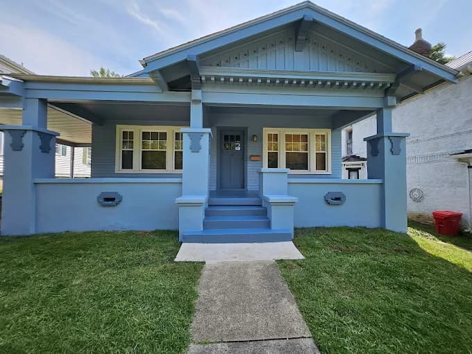 This is an image from Skywalkers Painting & Repairs, located in Ohio. The image shows a light blue craftsman-style home exterior with freshly painted siding, trim, and front porch columns.