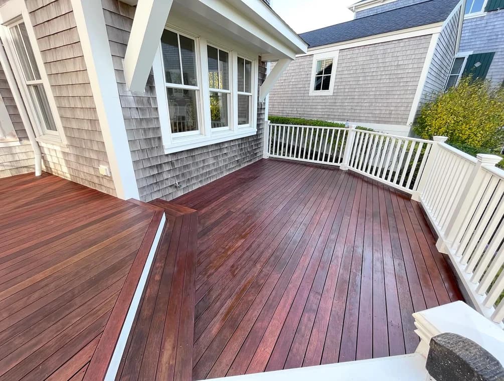Beautifully restored wooden deck with white railings completed by Cape Cod Fine Finishes LLC. The finish enhances both durability and visual appeal for this Massachusetts home.