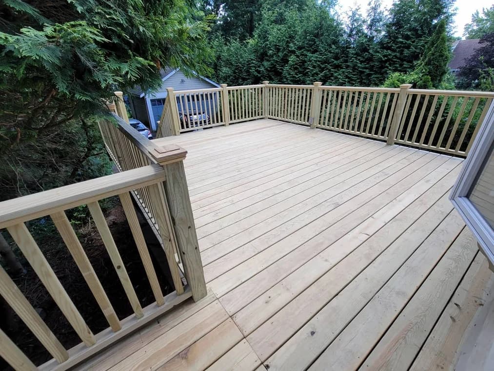 This is an image from Mark Tirondola Jr. Painting Contractor LLC in New Jersey. It displays a new wooden deck with light-colored boards and railings.