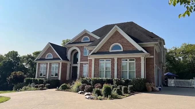 Painting project by New Direction Painting in Franklin, Tennessee. The image shows a large brick home with white window trim.