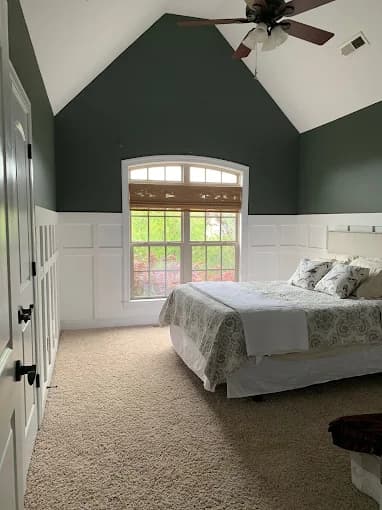 Interior painting project by Still Perfection Painting Co. in Belews Creek, North Carolina. The image shows green bedroom walls, white trim, and an arched window.