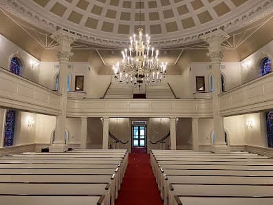 Interior painting project by CertaPro Painters of Fayetteville, NC in Lillington, NC. The image shows a church sanctuary with white pews and a chandelier.