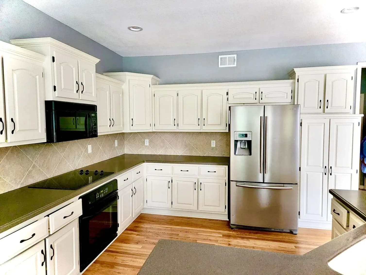 This is an image from Cougar Painting LLC. The image is interior kitchen in Kansas City KS with freshly painted white cabinets and updated hardware.