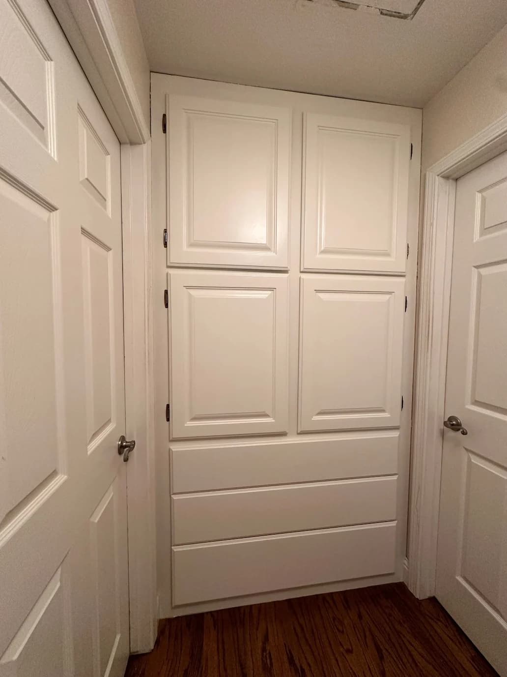 This is an image from Browder Painting Company, located in California. The image shows freshly painted white built-in hallway cabinets with recessed panel doors and drawers, clean trim lines, and a smooth professional finish.