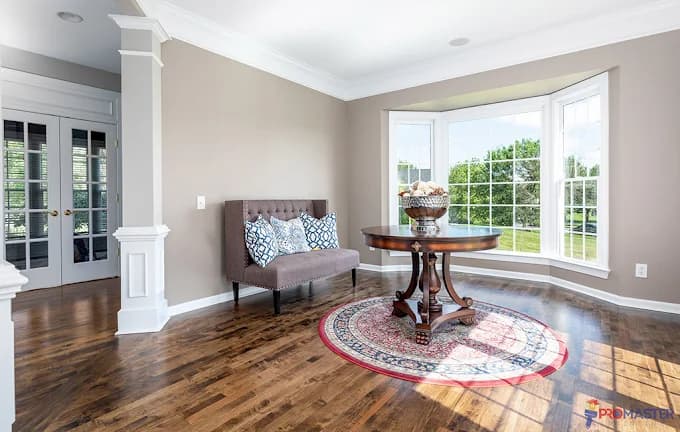 Interior painting project by Johnson Painting Co. & More in Kernersville, North Carolina. The image shows an entry room with white trim, large windows, wood floors, and a table.